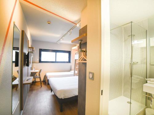a hotel room with a bed and a shower at ibis budget Site du Futuroscope in Chasseneuil-du-Poitou