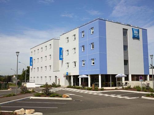 a white and blue building with a parking lot at Ibis Budget Chalon Sur Saone Nord in Chalon-sur-Saône