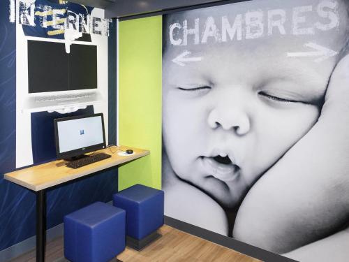 a room with a desk with a computer and a baby at ibis budget Goussainville Charles de Gaulle in Goussainville