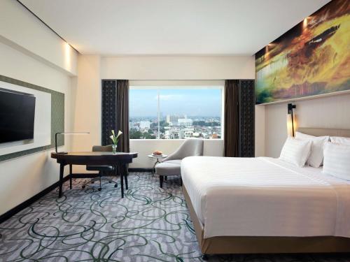a hotel room with a bed and a desk at Grand Mercure Medan Angkasa in Medan