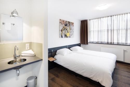 a hotel room with a bed and a sink at Hotel Blooker in Renesse