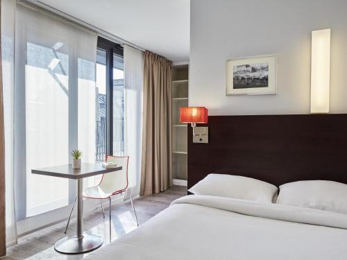 Un dormitorio con una cama y una mesa y una ventana. en Aparthotel Adagio Access Paris Bastille, en París