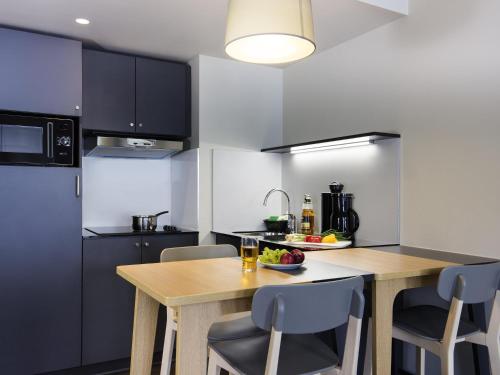 a kitchen with a wooden table and chairs at Aparthotel Adagio access München City Olympiapark in Munich