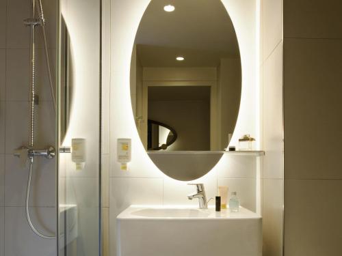 a bathroom with a sink and a mirror at Aparthotel Adagio access München City Olympiapark in Munich