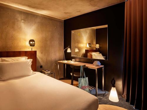 a bedroom with a bed and a desk and a mirror at Mama Shelter Paris East in Paris