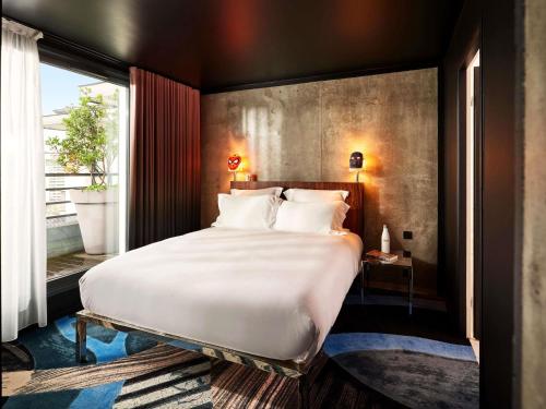 a bedroom with a large white bed and a window at Mama Shelter Paris East in Paris