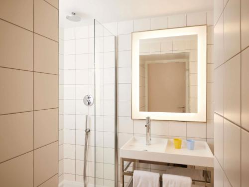 a white bathroom with a sink and a mirror at Mama Shelter Paris East in Paris