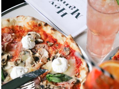 a pizza on a plate with a fork and a drink at Mama Shelter Paris East in Paris