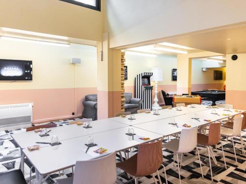 a conference room with tables and chairs and a screen at Mama Shelter Paris East in Paris