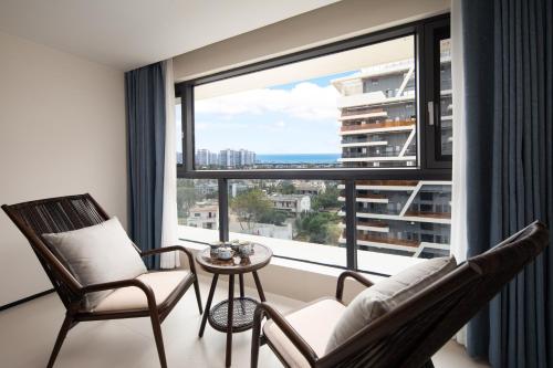a room with two chairs and a table and a large window at 海棠湾罗岚度假酒店-Haitang Bay Luolan Resort Hotel in Fenjietang