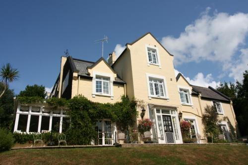 a yellow house with white windows and bushes at Bedford Lodge in Shanklin