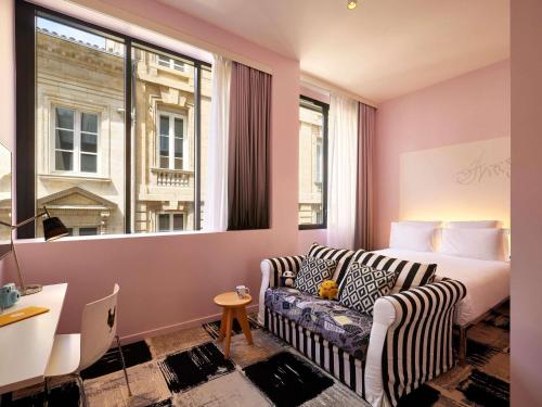a hotel room with a couch and a bed and a window at Mama Shelter Bordeaux Centre in Bordeaux