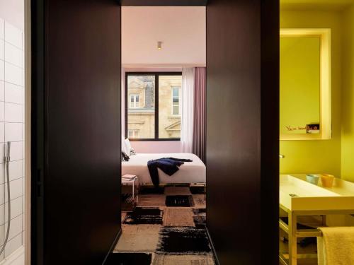 a room with a bedroom with a bed and a window at Mama Shelter Bordeaux Centre in Bordeaux