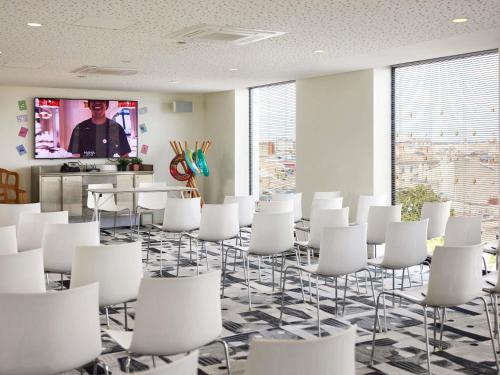 a conference room with white chairs and a tv at Mama Shelter Bordeaux Centre in Bordeaux