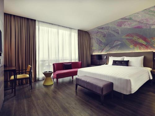 a hotel room with a large bed and a desk at Mercure Karawang in Karawang
