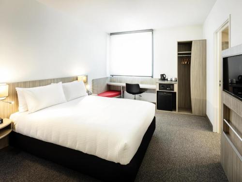a hotel room with a bed and a desk at Ibis Mackay in Mackay