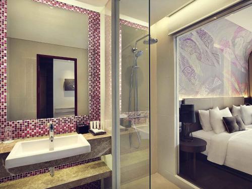 a bathroom with a sink and a bed and a mirror at Mercure Karawang in Karawang