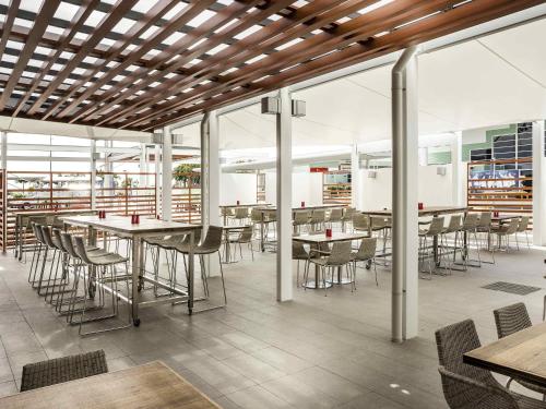 a dining room with tables and chairs and windows at Ibis Mackay in Mackay