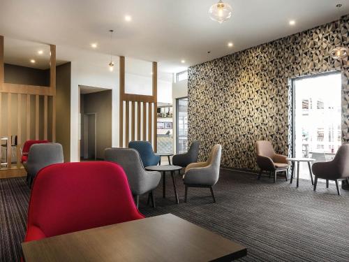 a waiting room with chairs and tables and a wall at Ibis Mackay in Mackay
