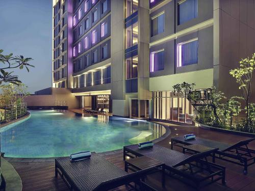 a hotel with a swimming pool in front of a building at Mercure Karawang in Karawang