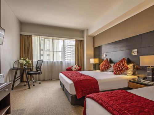 a hotel room with two beds and a desk at Mercure Wellington Abel Tasman in Wellington