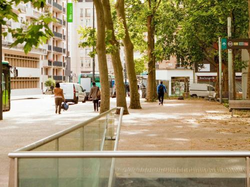 people walking down a street in a city with trees at ibis Styles Paris Mairie de Montreuil in Montreuil
