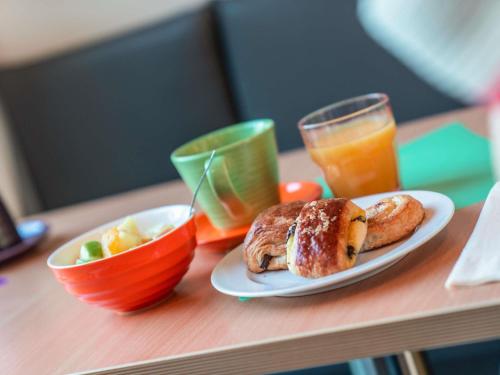 a table with a plate of food and a glass of orange juice at ibis Styles Paris Mairie de Montreuil in Montreuil