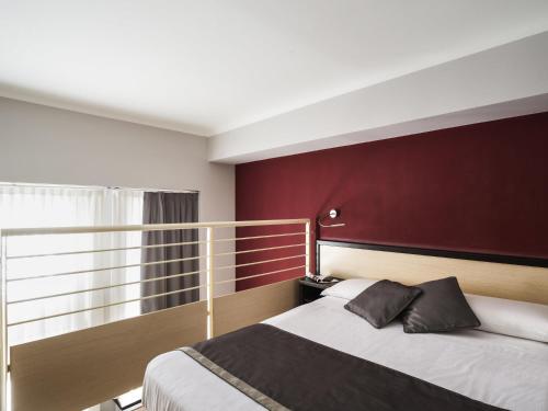 a bedroom with a large bed with a red wall at Ibis Styles Milano Centro in Milan
