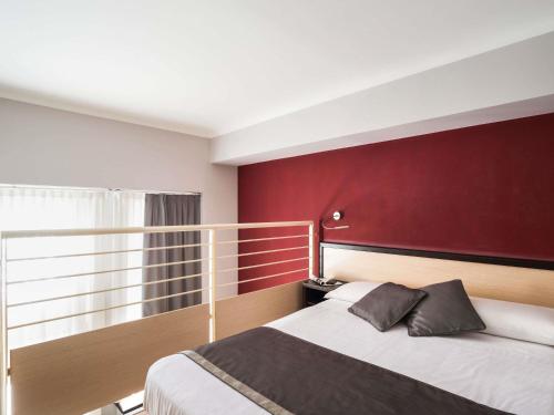 a bedroom with a large bed with a red wall at Ibis Styles Milano Centro in Milan