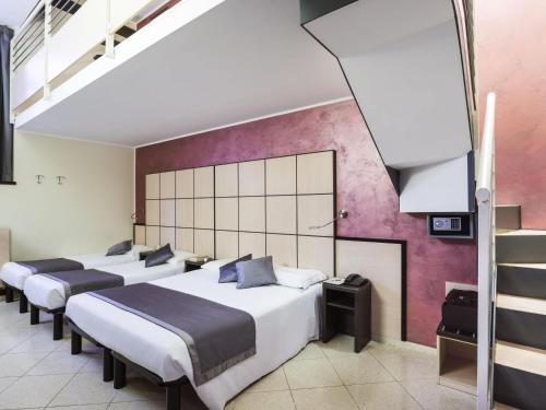 a group of four beds in a room at Ibis Styles Milano Centro in Milan