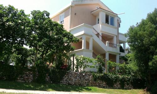 a large white house with a stone wall at Apartments Villa Andjela in Budva