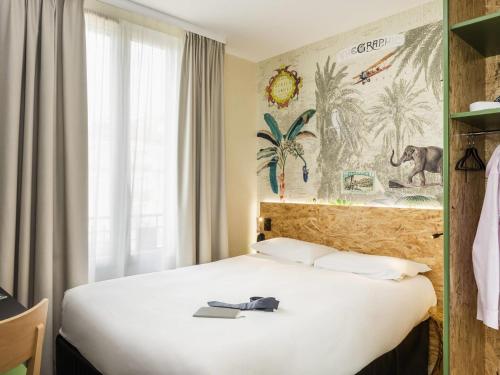 una stanza d'albergo con un letto con un libro sopra di ibis Styles Paris Boulogne Marcel Sembat a Boulogne-Billancourt