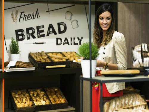 マドリードにあるノボテル マドリード センターのパン屋のカウンターの後ろに食べ物を持って立っている女性