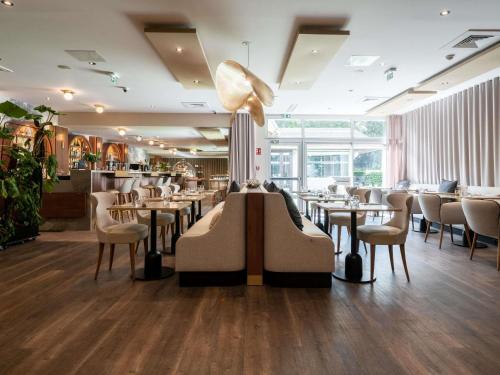 a restaurant with tables and chairs and a lamp at Mercure Paris Ouest Saint Germain in Saint-Germain-en-Laye