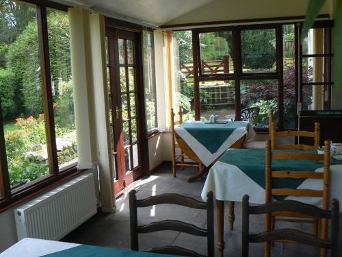 um quarto com uma mesa, cadeiras e janelas em Forest How Guest House em Eskdale