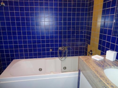 a blue tiled bathroom with a tub and a sink at Villa Bocca del Pozzo in Gagliano del Capo