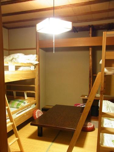 a room with bunk beds with a table and a light at Guesthouse Shirahama in Shirahama