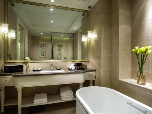 a bathroom with a tub and a sink and a mirror at The Sebel Xining-Managed By Sofitel in Xining