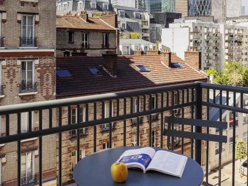 a book and an apple on a table on a balcony at Aparthotel Adagio Access La Défense Puteaux in Puteaux