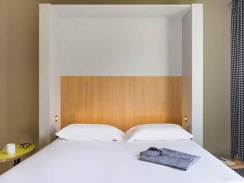 a bedroom with a white bed with a wooden headboard at Aparthotel Adagio Access La Défense Puteaux in Puteaux