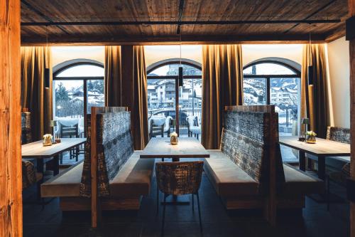 a restaurant with tables and chairs and windows at Burgstadl Aparthotel & Restaurant in Ladis