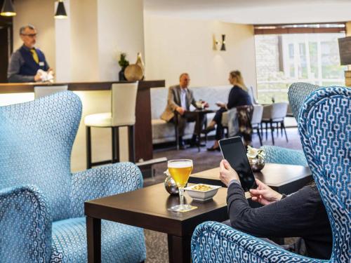 a group of people sitting around a table with a tablet at Mercure Maurepas Saint Quentin in Maurepas