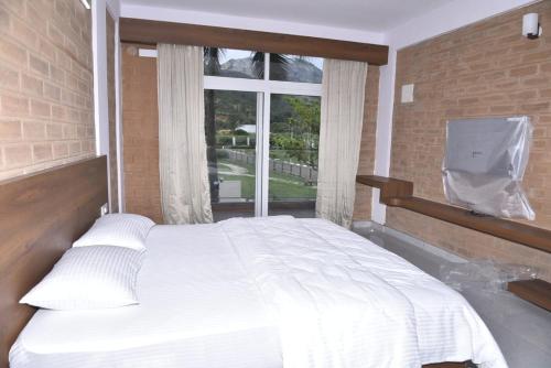 a bedroom with a white bed and a window at Brick House at Nandi in Bengaluru