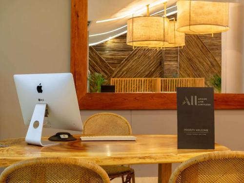 a wooden table with a laptop computer and chairs at Mercure Santa Marta Emile in Santa Marta