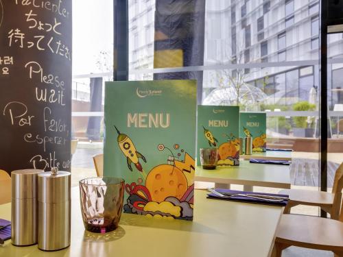 a table with some books and a glass on it at ibis Styles Paris Charles de Gaulle Airport in Roissy-en-France