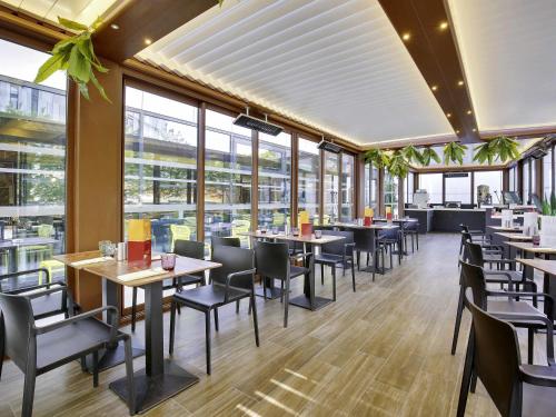 a restaurant with tables and chairs and windows at ibis Styles Paris Charles de Gaulle Airport in Roissy-en-France