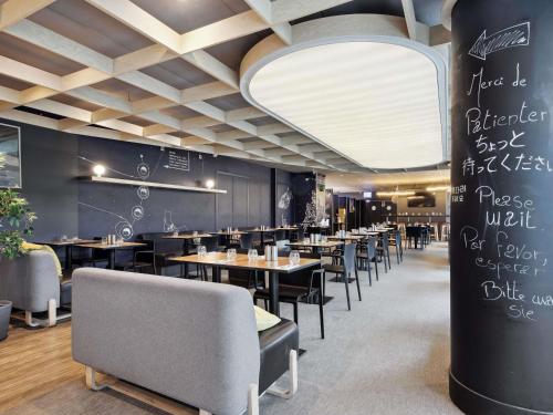 a dining room with tables and chairs and a chalkboard at ibis Styles Paris Charles de Gaulle Airport in Roissy-en-France
