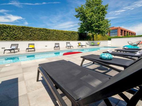 a pool with chaise lounge chairs and a swimming pool at Ibis Styles Toulouse Labège in Labège