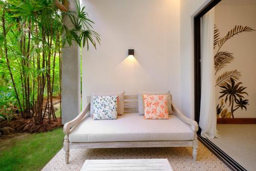 a white couch with pillows sitting on a porch at laïla, Seychelles, a Tribute Portfolio Resort in Mahe