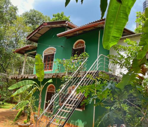 una casa verde en medio de un bosque en Amaya HomeStay, en Sigiriya